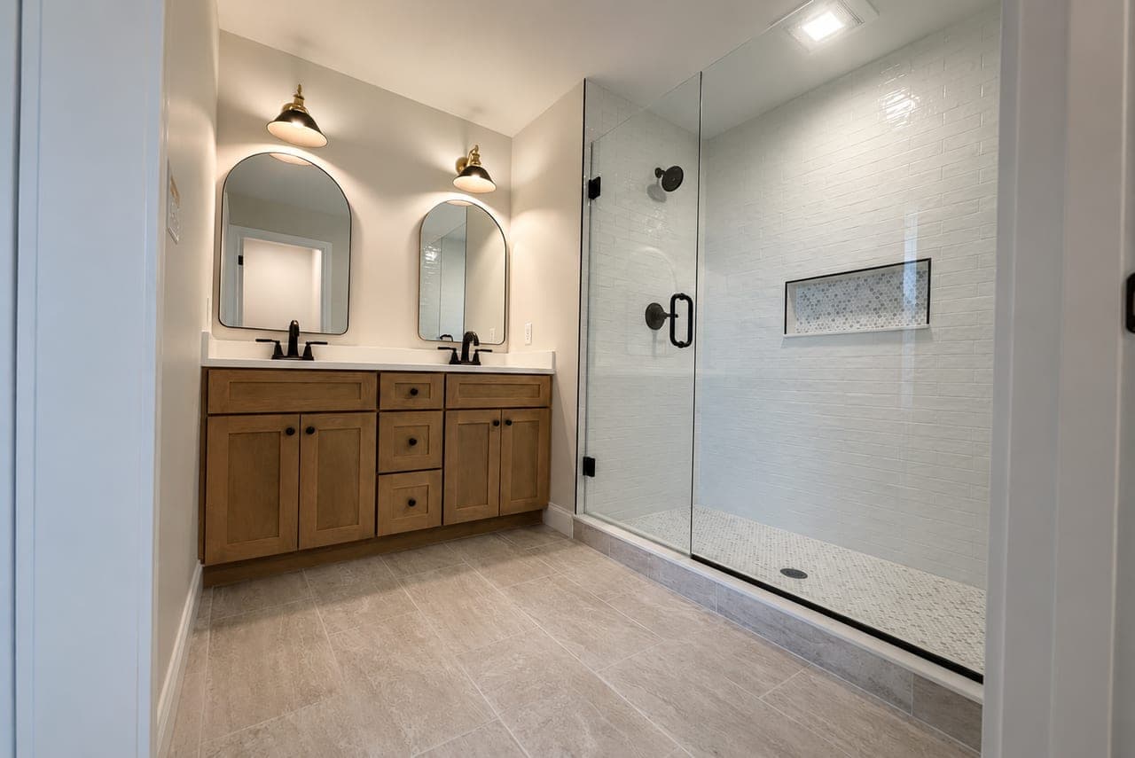 Hash Contracting Solutions craftsmanship: a finished bathroom remodel with a double vanity and walk-in tile shower.
